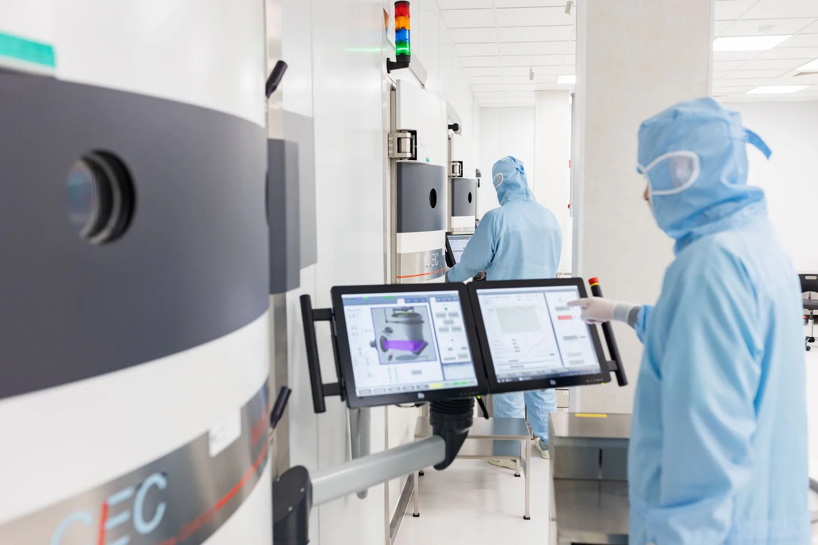 Eksma Optics cleanroom — operator at an optical coating machine